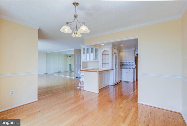 interior space featuring crown molding, white refrigerator with ice dispenser, light wood-style floors, and a chandelier