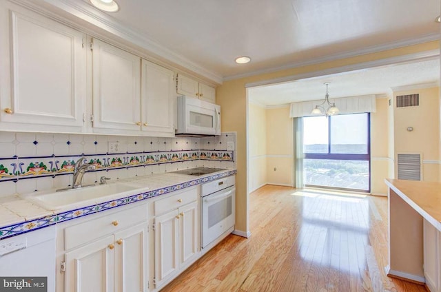 kitchen with visible vents, crown molding, light wood-type flooring, white appliances, and a sink