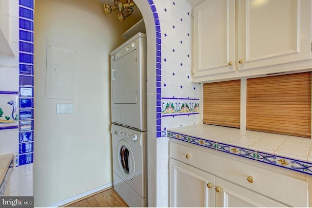 laundry room with laundry area, electric panel, and stacked washer / drying machine