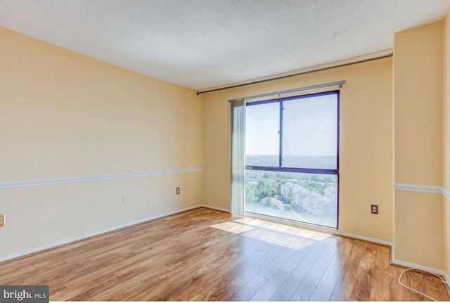 unfurnished room with wood finished floors, baseboards, and a textured ceiling