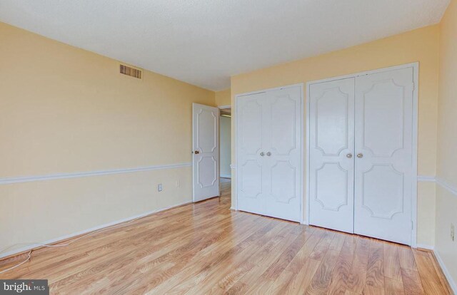 unfurnished bedroom with light wood-style floors, visible vents, and multiple closets