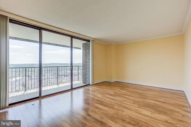 unfurnished room featuring ornamental molding, a textured ceiling, floor to ceiling windows, light wood-style floors, and baseboards