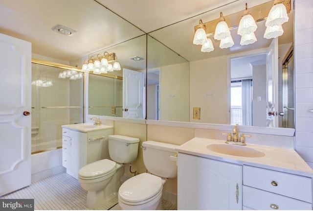 bathroom featuring tile patterned flooring, toilet, vanity, and bath / shower combo with glass door