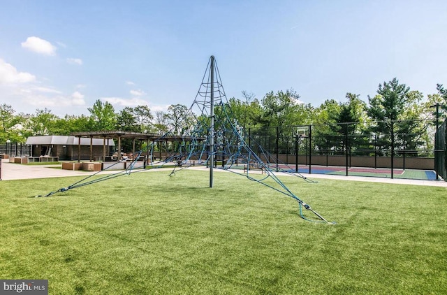 view of community featuring playground community, a yard, a pergola, and fence