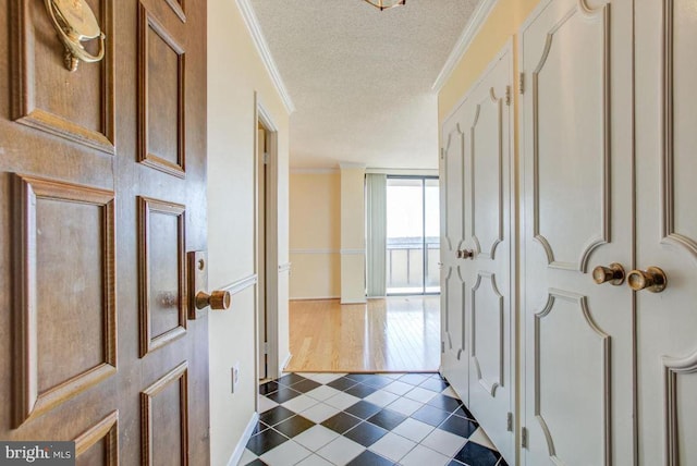 foyer entrance featuring a textured ceiling, baseboards, and ornamental molding