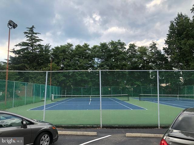 view of tennis court with community basketball court and fence