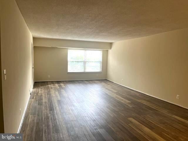 spare room with dark wood-type flooring and a textured ceiling