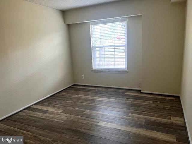 unfurnished room with wood finished floors, baseboards, and a textured ceiling