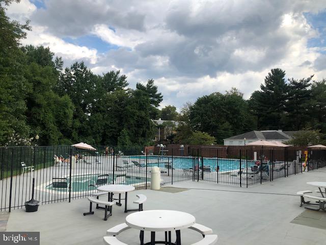 community pool with a patio area and fence