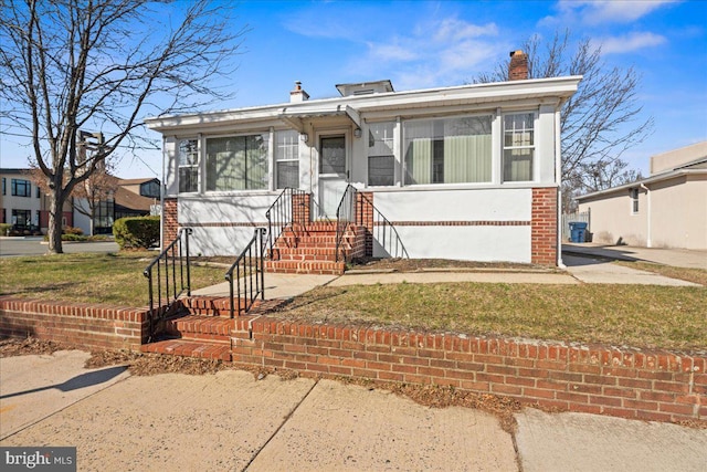 bungalow featuring brick siding and a chimney