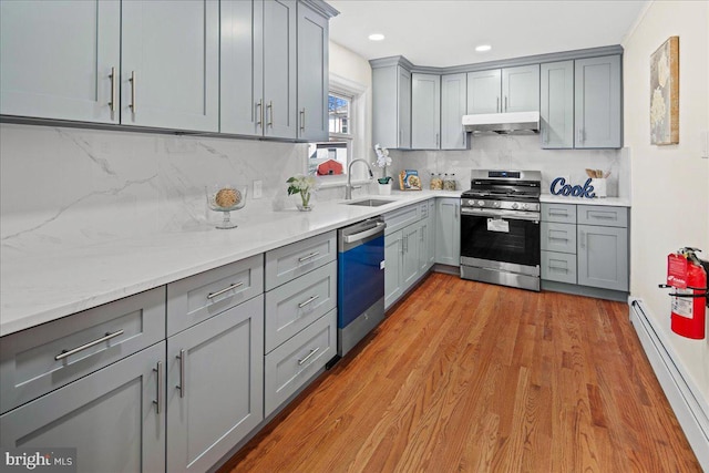 kitchen with a baseboard heating unit, under cabinet range hood, dishwasher, gray cabinets, and stainless steel gas stove