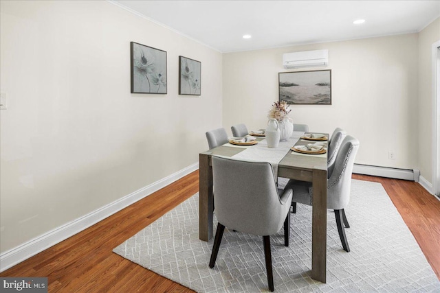 dining room with crown molding, baseboards, an AC wall unit, baseboard heating, and wood finished floors