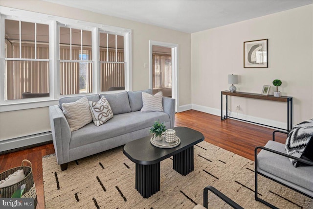 living area featuring baseboard heating, baseboards, and wood finished floors