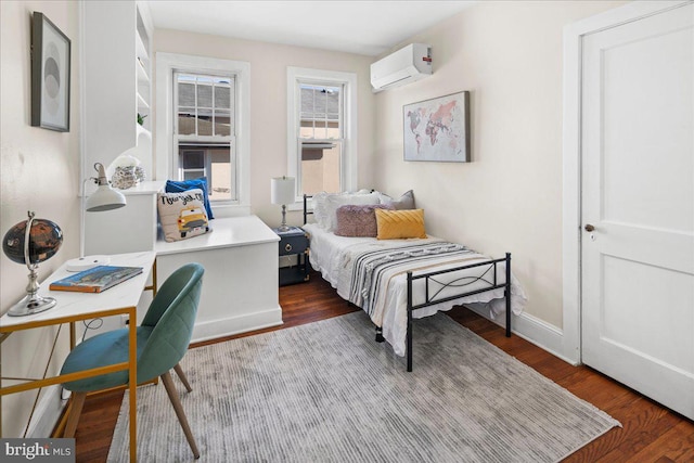 bedroom with an AC wall unit, wood finished floors, and baseboards