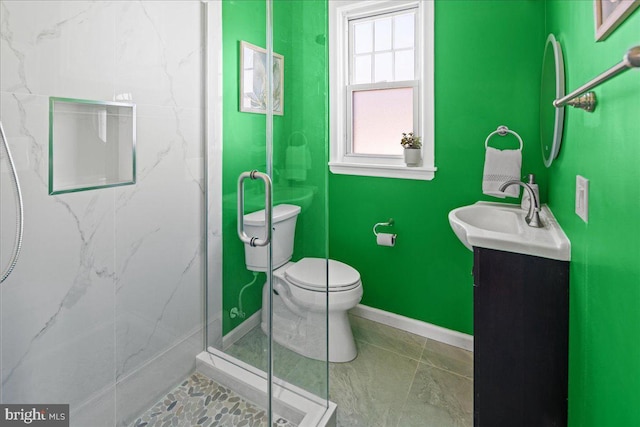 bathroom with baseboards, vanity, toilet, and a shower stall