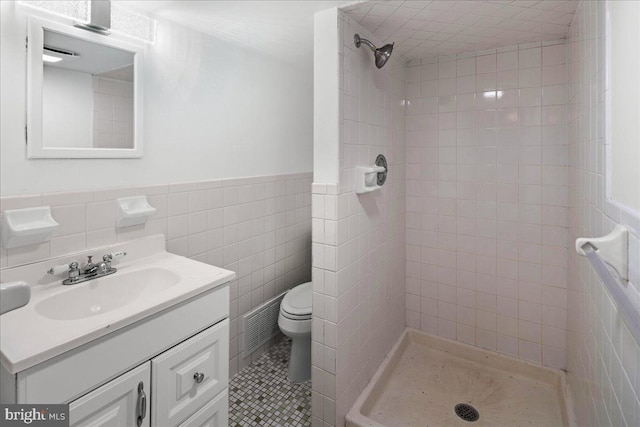 bathroom featuring vanity, a stall shower, wainscoting, tile walls, and toilet