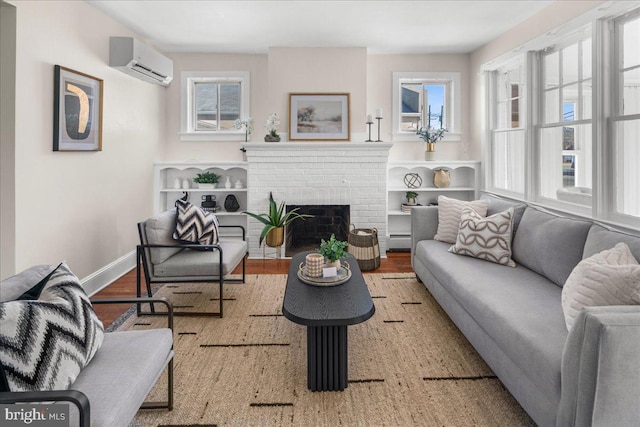 living area with wood finished floors, baseboards, a baseboard radiator, an AC wall unit, and a brick fireplace