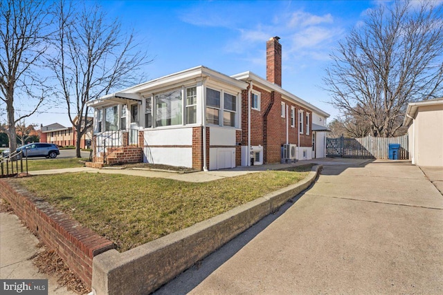 view of front of property with brick siding, a front lawn, fence, concrete driveway, and a chimney