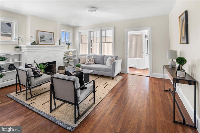 living area with a fireplace, baseboards, and wood-type flooring