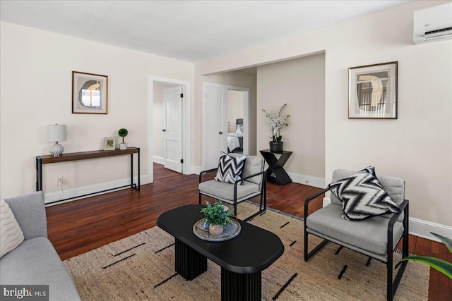 sitting room with baseboards, an AC wall unit, and wood finished floors