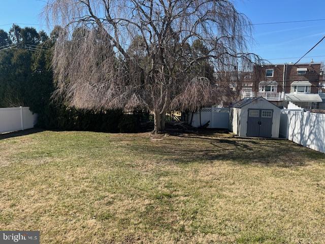 view of yard with a storage unit, an outdoor structure, and a fenced backyard