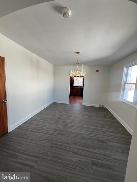 unfurnished dining area featuring visible vents, baseboards, dark wood-type flooring, and a chandelier