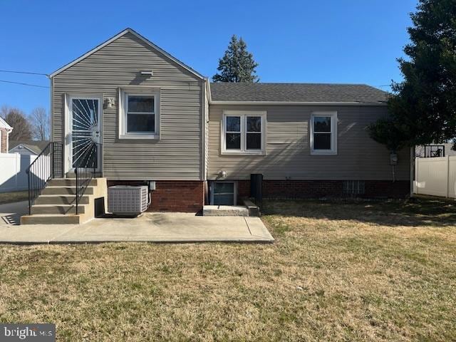 rear view of property featuring central air condition unit, a patio, a lawn, and fence