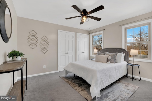 carpeted bedroom featuring two closets, baseboards, and a ceiling fan