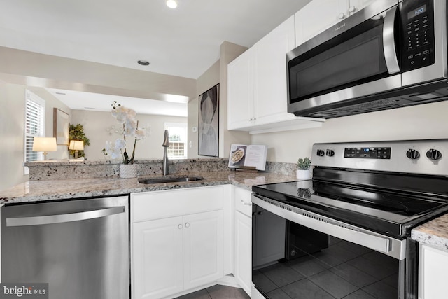 kitchen featuring a sink, white cabinets, light stone countertops, and stainless steel appliances