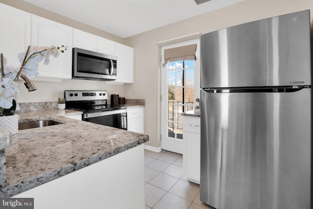 kitchen featuring visible vents, stainless steel appliances, white cabinets, light tile patterned floors, and light stone countertops