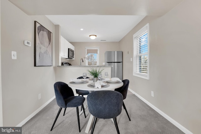 dining room featuring baseboards and light colored carpet