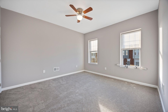 unfurnished room featuring a ceiling fan, carpet flooring, baseboards, and visible vents