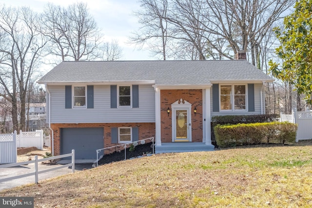 raised ranch with brick siding, fence, a chimney, driveway, and an attached garage