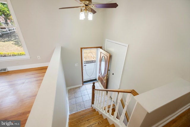 foyer entrance with baseboards, wood finished floors, ceiling fan, and a towering ceiling