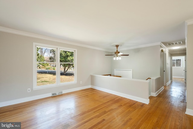 unfurnished room with light wood finished floors, visible vents, and ornamental molding