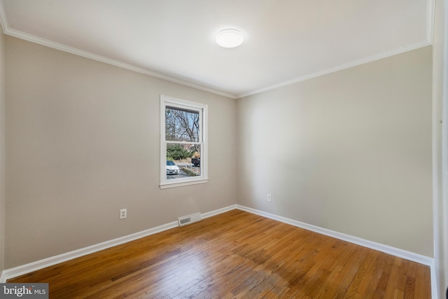 empty room with crown molding, baseboards, visible vents, and wood-type flooring