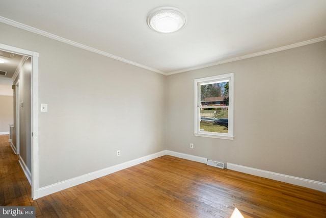 spare room with visible vents, ornamental molding, baseboards, and wood-type flooring