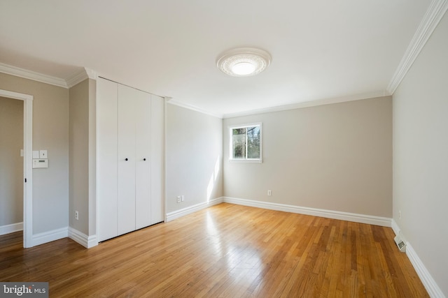 unfurnished bedroom featuring baseboards, light wood-style floors, and ornamental molding