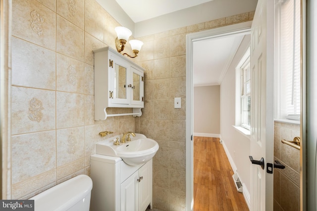 bathroom featuring visible vents, toilet, vanity, wood finished floors, and tile walls