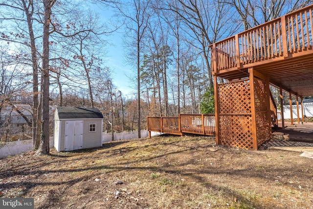 view of yard featuring a storage unit, an outbuilding, a deck, and fence