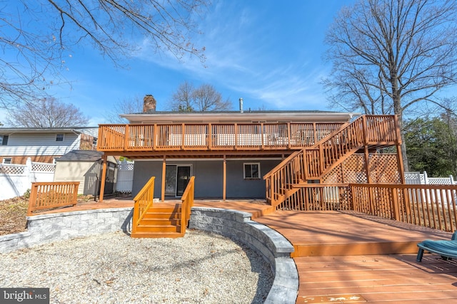 back of house featuring fence, a shed, a chimney, a deck, and an outdoor structure