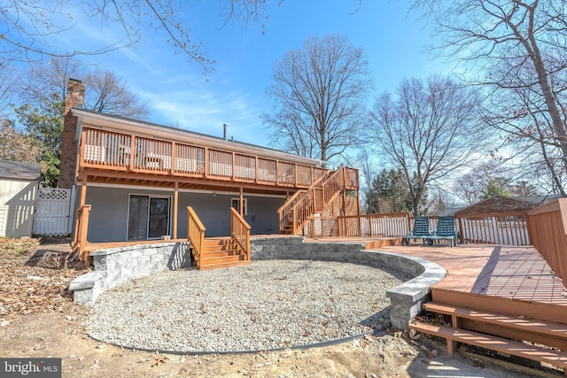 back of house with a wooden deck, a chimney, stairs, and stucco siding