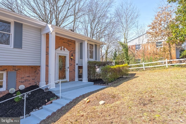 property entrance featuring brick siding and fence