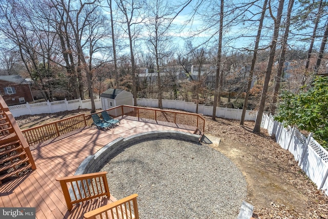 view of yard featuring a deck, an outdoor structure, a fenced backyard, and a shed