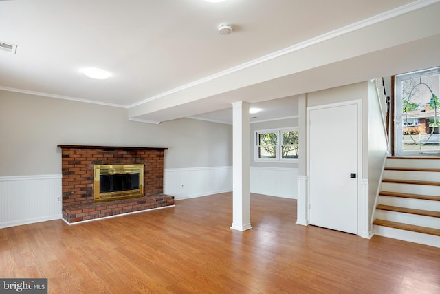 basement featuring stairs, ornamental molding, a wainscoted wall, and light wood-type flooring