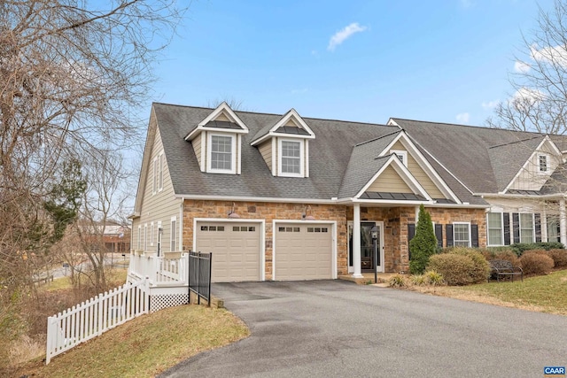 view of front of home featuring fence, stone siding, driveway, and roof with shingles