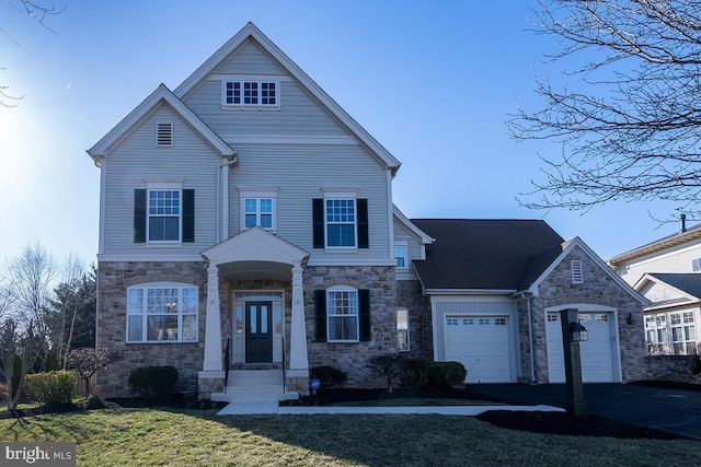 view of front facade featuring aphalt driveway, stone siding, an attached garage, and a front yard