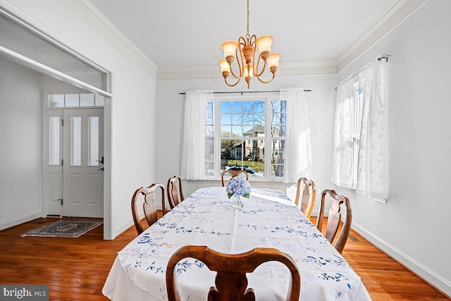 dining room featuring baseboards, crown molding, an inviting chandelier, and wood finished floors