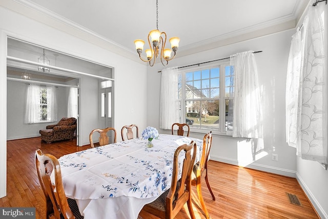 dining space with light wood-style flooring, visible vents, a chandelier, and ornamental molding