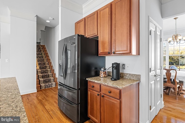 kitchen with stainless steel fridge with ice dispenser, light wood-type flooring, ornamental molding, brown cabinetry, and a notable chandelier